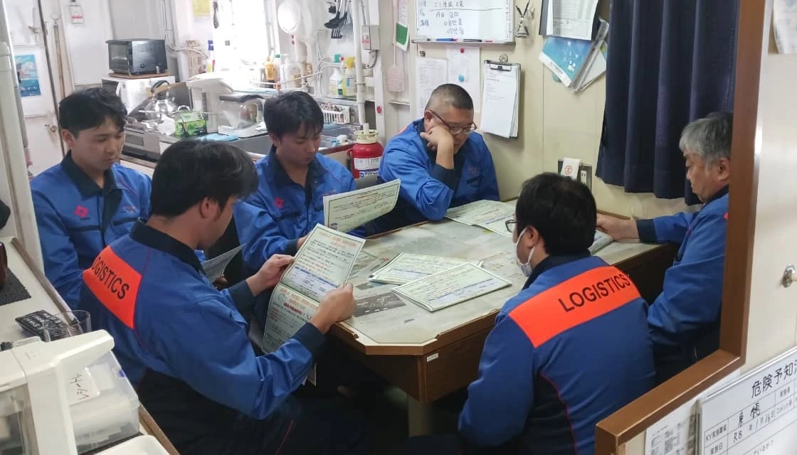 資料を確認しながら会議を行う船員たち