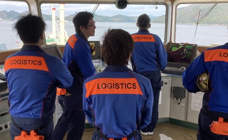 ブリッジ（船橋）で前方を確認しながら操船する航海士たちの背中