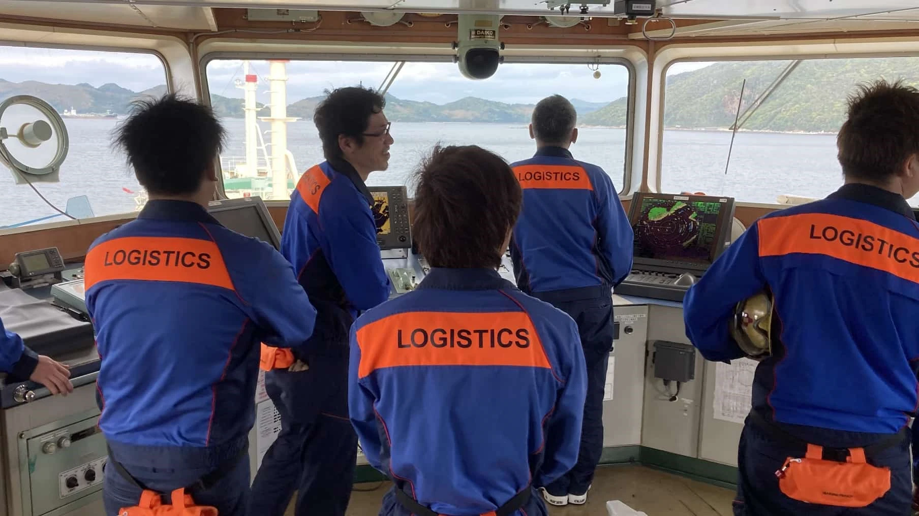 ブリッジ（船橋）で前方を確認しながら操船する航海士たちの背中