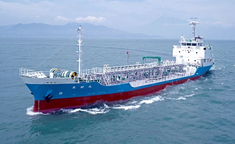 富士山を背景に海を進む青と赤の船体の貨物船