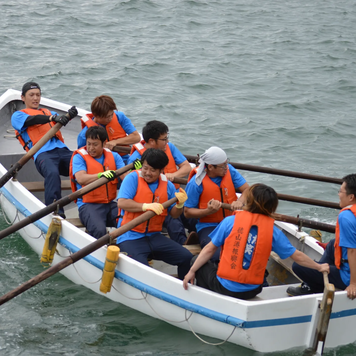  力を合わせてカッターボートを漕ぐ男性チーム