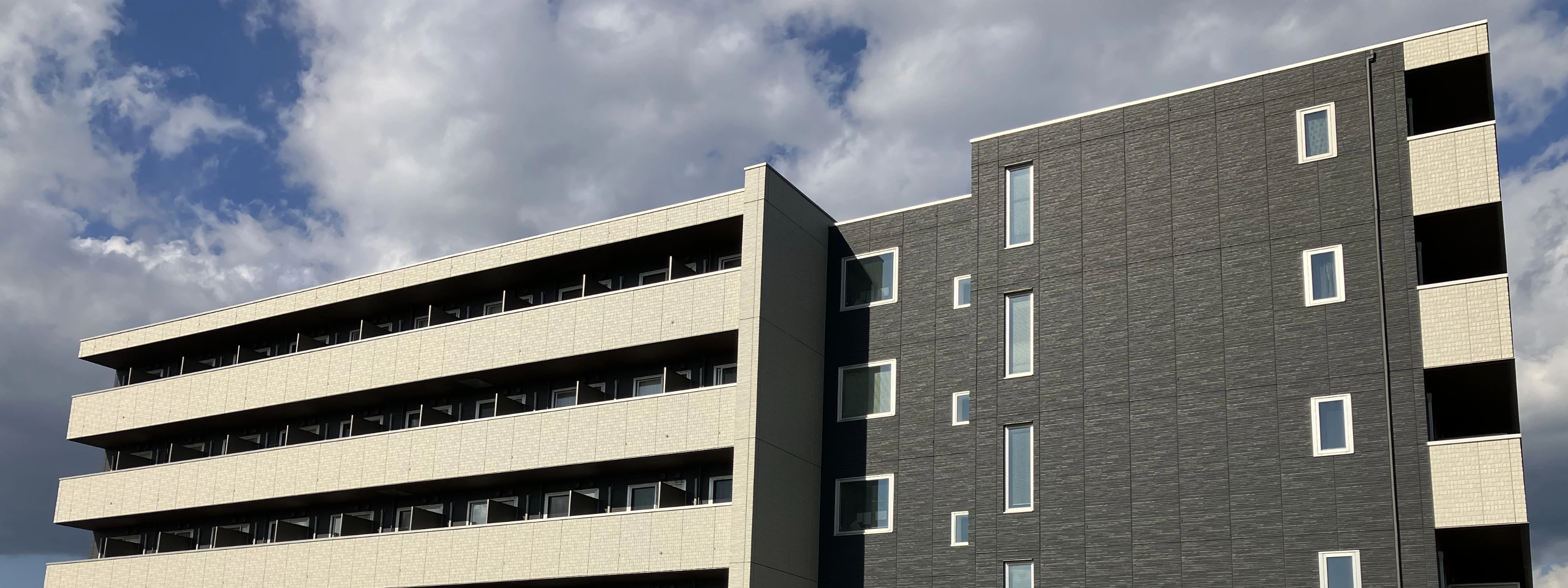 青空を背景にしたモダンな外観のマンション