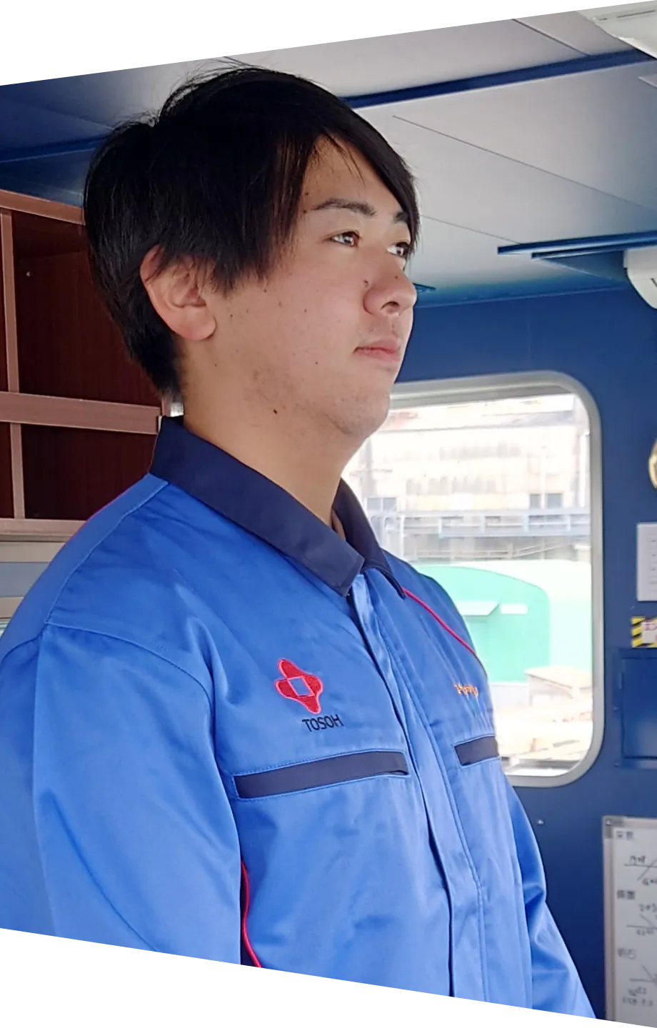 船橋（ブリッジ）で前方を注視する青い作業着の若手船員