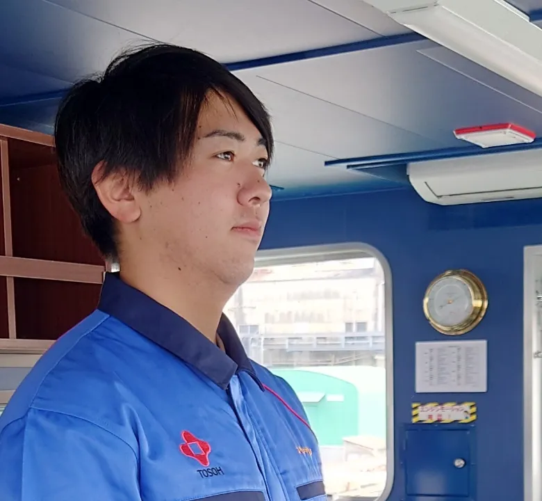 船橋（ブリッジ）で前方を注視する青い作業着の若手船員